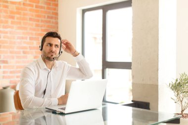 Yakışıklı pazarlamacı şaşkın ve kafası karışmış hissediyor, kafasını kaşıyor ve yan tarafa bakıyor.