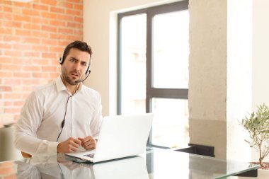 handsome telemarketer feeling puzzled and confused, with a dumb, stunned expression looking at something unexpected