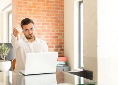 Yakışıklı iş adamı kızgın, sinirli, hayal kırıklığına uğramış ya da hoşnutsuz, ciddi bir bakışla başparmağını kaldırıyor.