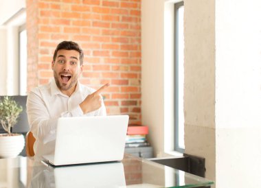 Yakışıklı iş adamı heyecanlı ve şaşırmış görünüyor. Yana ve yukarı doğru uzayı gösteriyor.