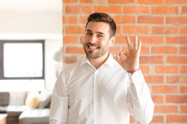 Yakışıklı iş adamı kendini mutlu, rahat ve tatmin olmuş hisseder. Onayını iyi bir hareketle gösterir.