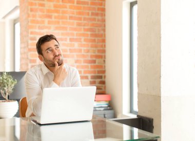 Yakışıklı iş adamı düşünüyor, kuşkulu ve şaşkın hissediyor, farklı seçenekleri var, hangi kararı vereceğini merak ediyor.