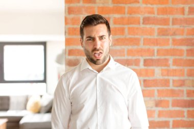 Yakışıklı iş adamı iğrenmiş ve rahatsız olmuş hissediyor, dilini dışarı çıkarıyor, iğrenç ve iğrenç bir şeyden hoşlanmıyor.