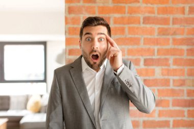 Yakışıklı işadamı şaşırmış, ağzı açık, şok olmuş, yeni bir düşünce, fikir ya da konsept keşfediyor.