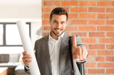 Yakışıklı mimar gururla gülümsüyor ve bir numaralı pozunu başarıyla veriyor, kendini lider gibi hissediyor.