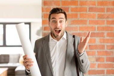 Yakışıklı mimar kendini mutlu, şaşırmış ve neşeli hissediyor. Pozitif bir tavırla gülümsüyor. Bir çözüm ya da fikir buluyor.