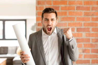 Yakışıklı mimar sinirli bir ifadeyle ya da yumruklarıyla başarıyı kutlarken agresif bir şekilde bağırıyor.