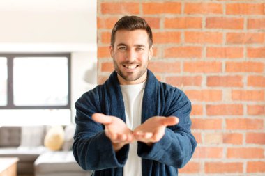 Yakışıklı adam mutlu bir şekilde gülümsüyor arkadaş canlısı, kendinden emin, olumlu bakışlı, bir nesne ya da konsept sunuyor ve gösteriyor.