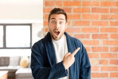 Yakışıklı adam heyecanlı ve şaşırmış görünüyor. Yana ve yukarı doğru uzayı gösteriyor.