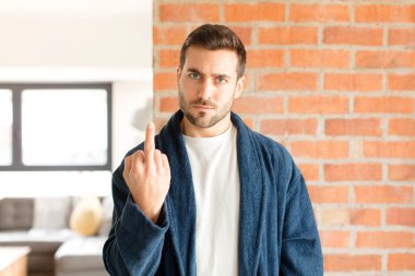 Yakışıklı adam kızgın, sinirli, isyankar ve agresif orta parmağını sallayarak karşılık veriyor.