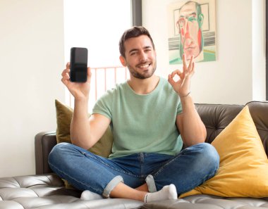 Yakışıklı adam kendini mutlu, rahat ve tatmin olmuş hissediyor. Onayını iyi bir hareketle gösteriyor. Gülümsüyor.