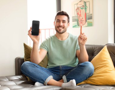 Yakışıklı bir adam gülümsüyor ve arkadaş canlısı görünüyor. Bir numara ya da ilk eli önde, geriye doğru sayıyor.