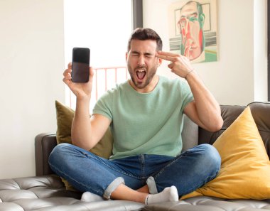 Yakışıklı adam mutsuz ve stresli görünüyor, intihar jesti elle silah işareti yapıyor, kafasını işaret ediyor.