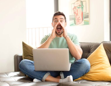 Yakışıklı adam mutlu, heyecanlı ve pozitif hissediyor. Elleri ağızda, bağırarak bağırıyor.