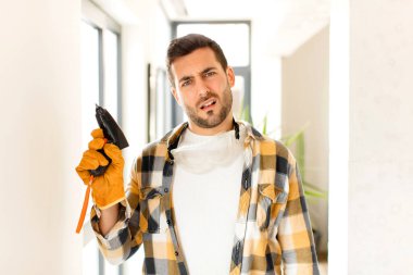 handyman feeling puzzled and confused, with a dumb, stunned expression looking at something unexpected