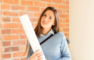 pretty architect feeling puzzled and confused, with a dumb, stunned expression looking at something unexpected