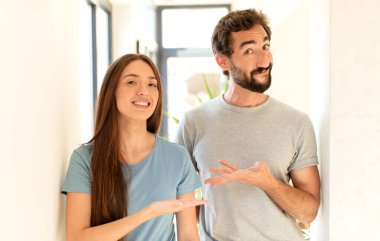 Genç çift mutlu bir şekilde gülümsüyor, mutlu hissediyorlar ve fotokopi alanında avucunun içinde bir konsept gösteriyorlar.