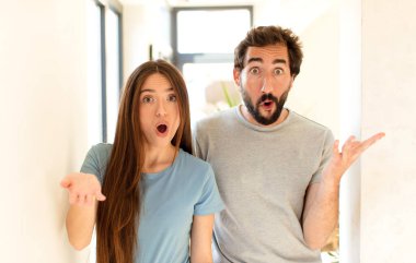 Genç çift ağzı açık ve şaşırmış, şok olmuş ve hayrete düşmüş.