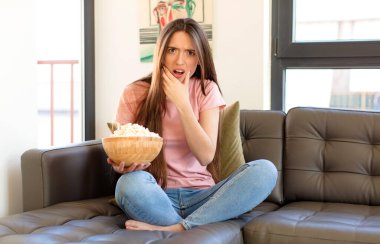 Ağzı ve gözleri açık ve elleri çenesinde, nahoş bir şekilde şokta, ne diyor ya da vay be