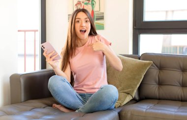 Güzel bir kadın mutlu, şaşırmış ve gururlu hissediyor, heyecanlı ve şaşkın bir bakışla kendini işaret ediyor.