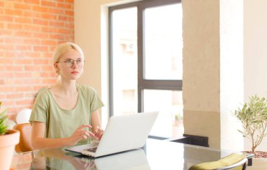 Evde dizüstü bilgisayar kullanan genç ve güzel bir kız.