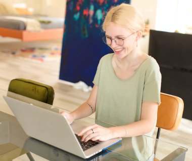 Evde dizüstü bilgisayar kullanan genç ve güzel bir kız.