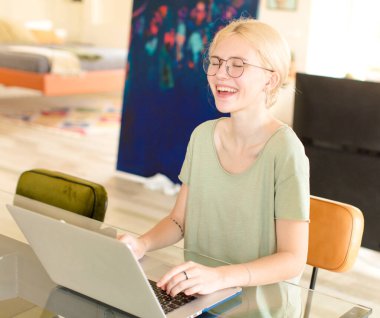 Evde dizüstü bilgisayar kullanan genç ve güzel bir kız.