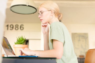 Evde dizüstü bilgisayar kullanan genç ve güzel bir kız.