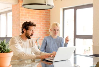 Genç çift dizüstü bilgisayar kullanıyor.