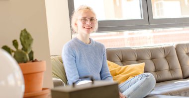 Evdeki kanepede oturan güzel kız.