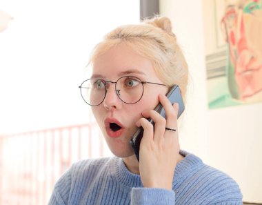 Evdeki genç ve güzel kız telefon kullanıyor.