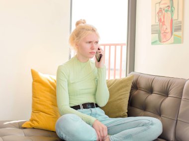 Genç ve güzel bir kız telefonunu evde kullanıyor.