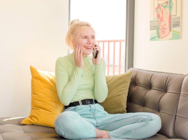 Genç ve güzel bir kız telefonunu evde kullanıyor.