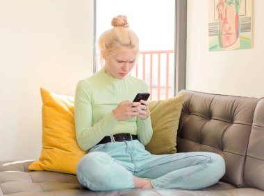 Genç ve güzel bir kız telefonunu evde kullanıyor.