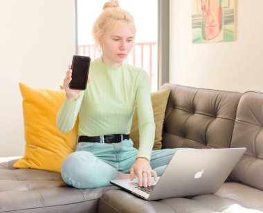 Evde dizüstü bilgisayar kullanan genç ve güzel bir kız.