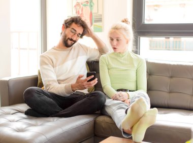 Evde akıllı telefon kullanan genç bir çift.