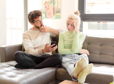 Evde akıllı telefon kullanan genç bir çift.