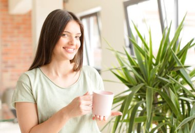 Genç güzel kız evde kahve içiyor.