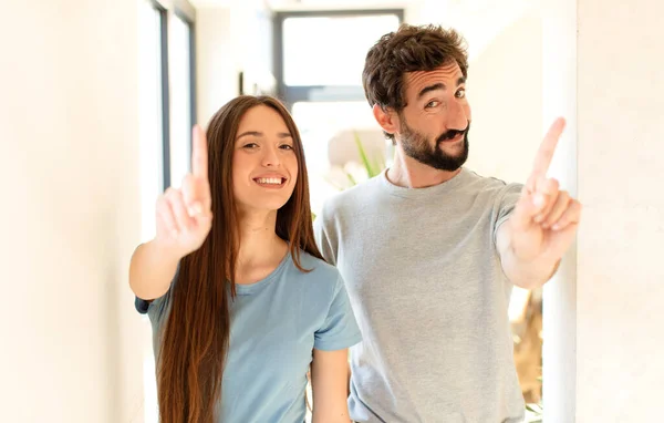 Joven Pareja Sonriendo Orgullosa Confiadamente Haciendo Número Uno Pose Triunfante —  Fotos de Stock