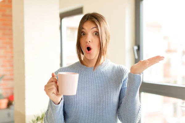 Mujer Bonita Mirando Sorprendida Conmocionada Con Mandíbula Caída Sosteniendo Objeto —  Fotos de Stock