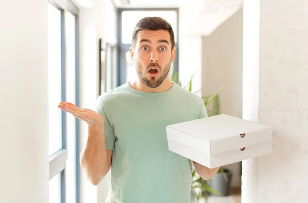 Hombre Guapo Mirando Sorprendido Sorprendido Con Mandíbula Caída Sosteniendo Objeto — Foto de Stock