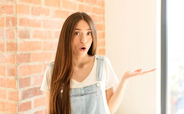 Mujer Bonita Mirando Sorprendida Conmocionada Con Mandíbula Caída Sosteniendo Objeto —  Fotos de Stock