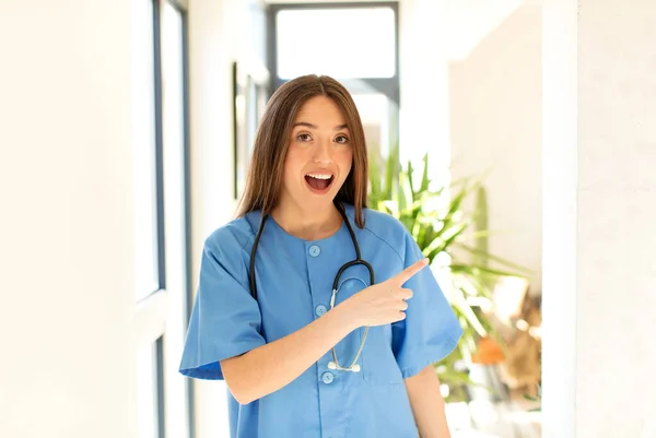 Красива Медсестра Виглядає Схвильованою Здивованою Вказуючи Бік Вгору Щоб Копіювати — стокове фото