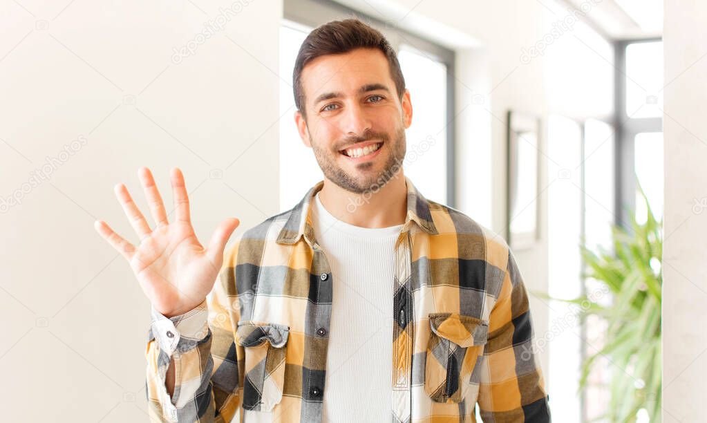 handsome man smiling and looking friendly, showing number five or fifth with hand forward, counting down