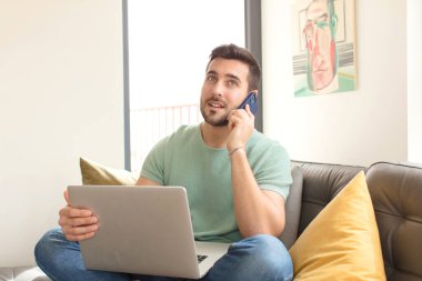 Genç yakışıklı adam akıllı telefonunu evde kullanıyor.