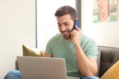 Genç yakışıklı adam akıllı telefonunu evde kullanıyor.