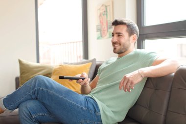 Genç yakışıklı bir adam televizyon kanalını seçiyor.