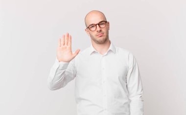 Kel adam ciddi, sert, hoşnutsuz ve kızgın görünüyor. Avuç içini açıp jesti durduruyor.