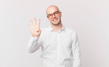 Kel adam gülümsüyor ve arkadaş canlısı görünüyor, 4 ya da 4 numarayı gösteriyor, eli önde, geriye doğru sayıyor.