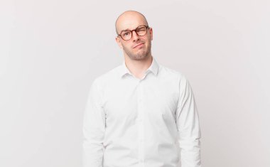 Kafası karışmış, kafası karışmış, sinirsel bir hareketle dudağını ısıran, sorunun cevabını bilmeyen kel bir adam.